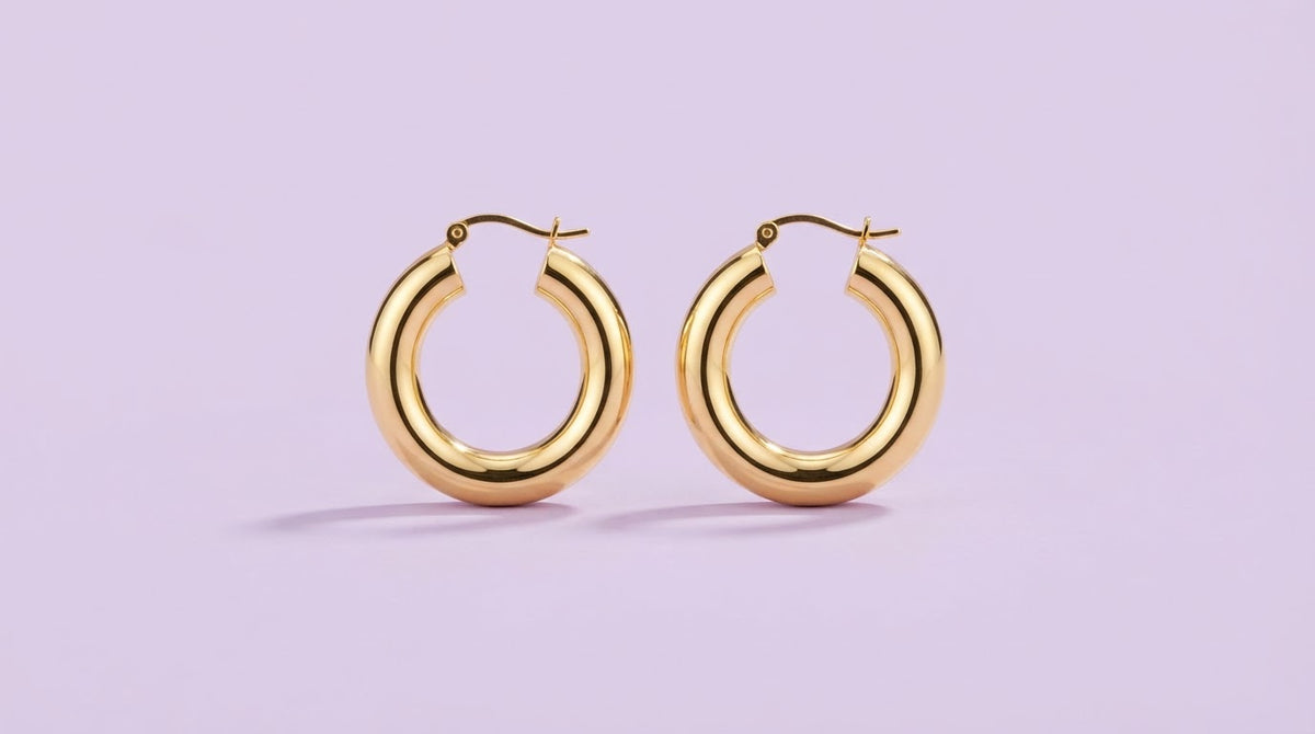 Chunky gold hoop earrings on a lilac background