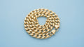 Chunky gold curb chain bracelet on a soft blue background