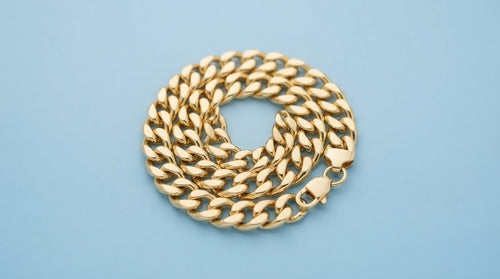 Chunky gold curb chain bracelet on a soft blue background