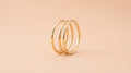Three thin gold stacking rings on a peach background