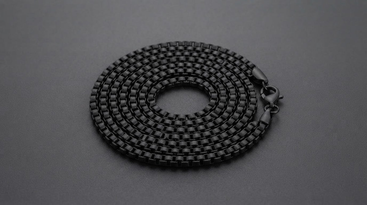 Matte black steel box chain necklace for men on a charcoal background