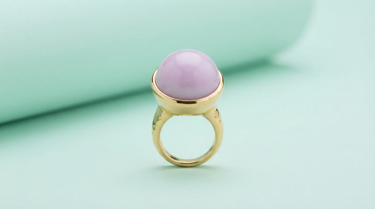 Gold statement ring with a large lilac stone on a mint background