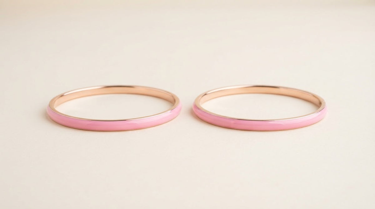Two slim pink enamel bangles on a cream background