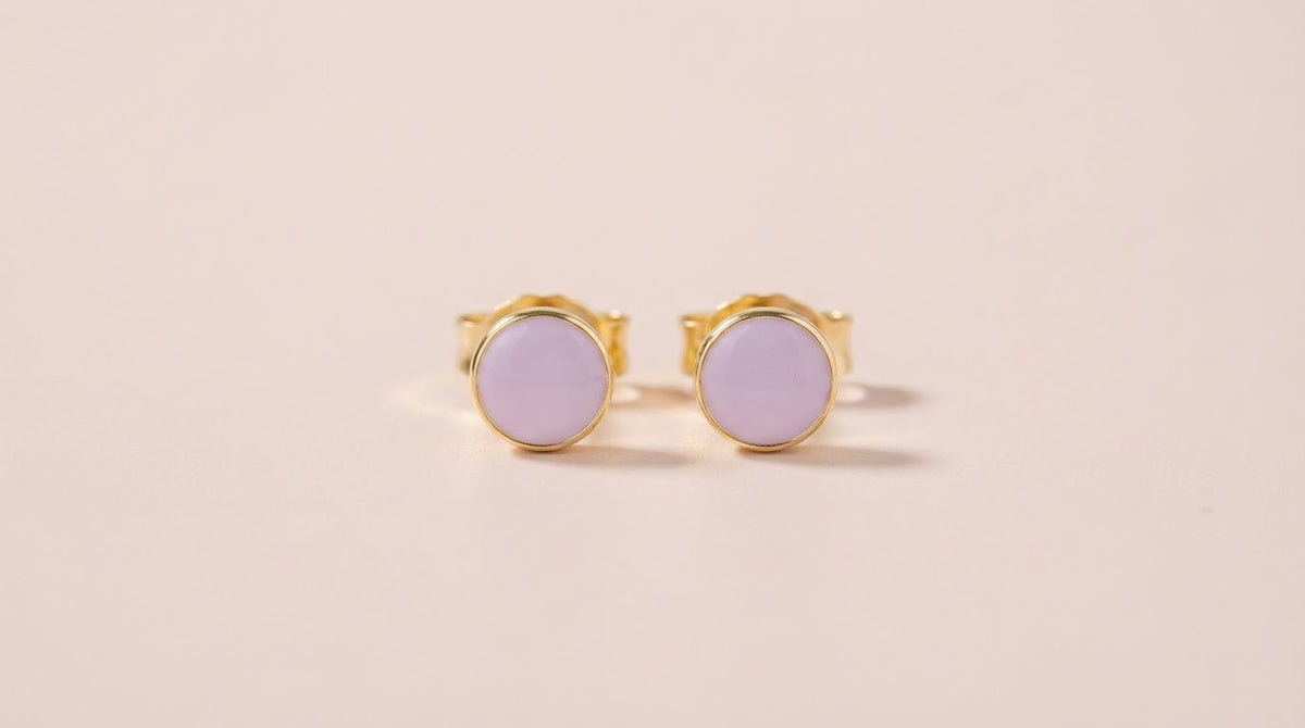 Lilac enamel stud earrings on a blush background